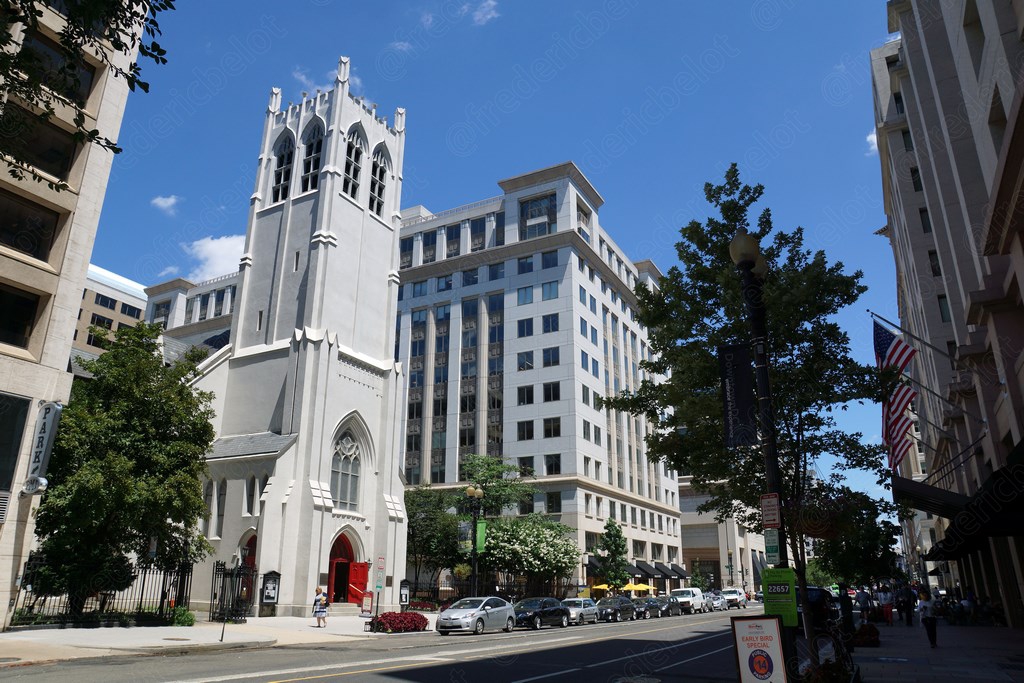Une église néogothique blanche s'élève entre des immeubles de bureaux.