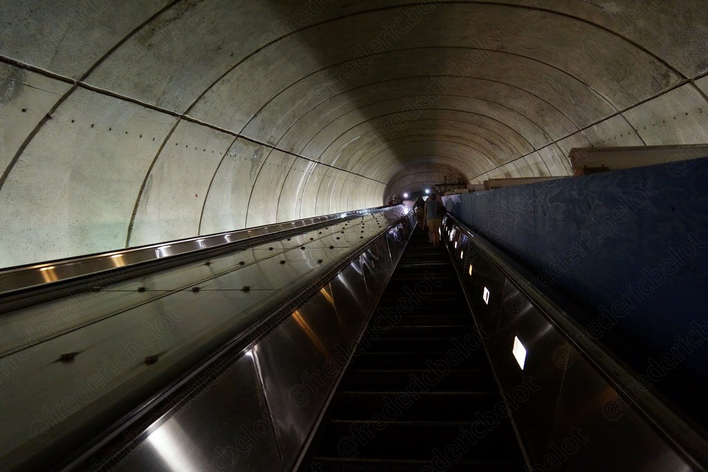 Un tunnel du métro vu en perspective, escalator menant vers la sortie.