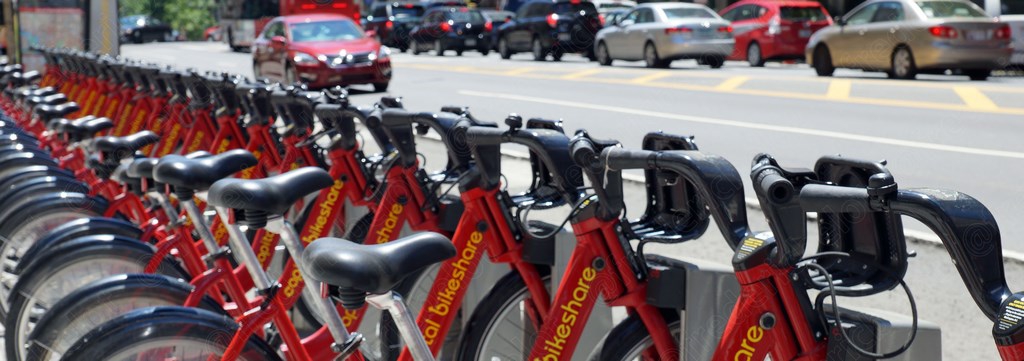 Une rangée de vélos en libre-service alignés le long d'une avenue.