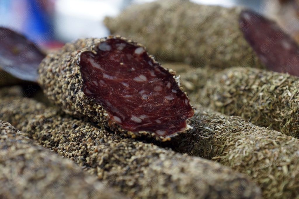 Une tranche de saucisson sec entamée posée sur d'autres saucissons.