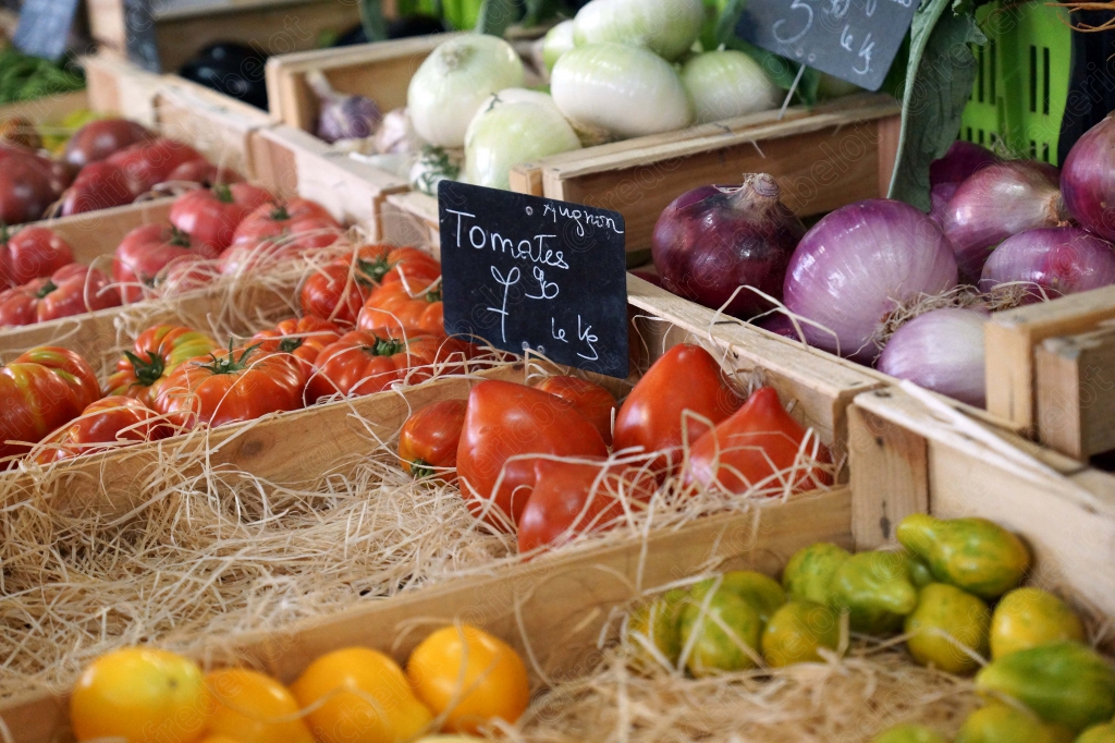 Un étal de tomates et d'oignons rouges et blancs, étiquette de prix.
