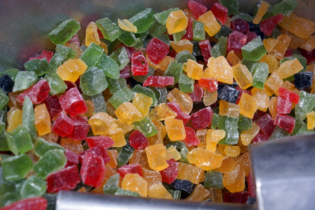 Des fruits confits multicolores présentés dans un présentoir.