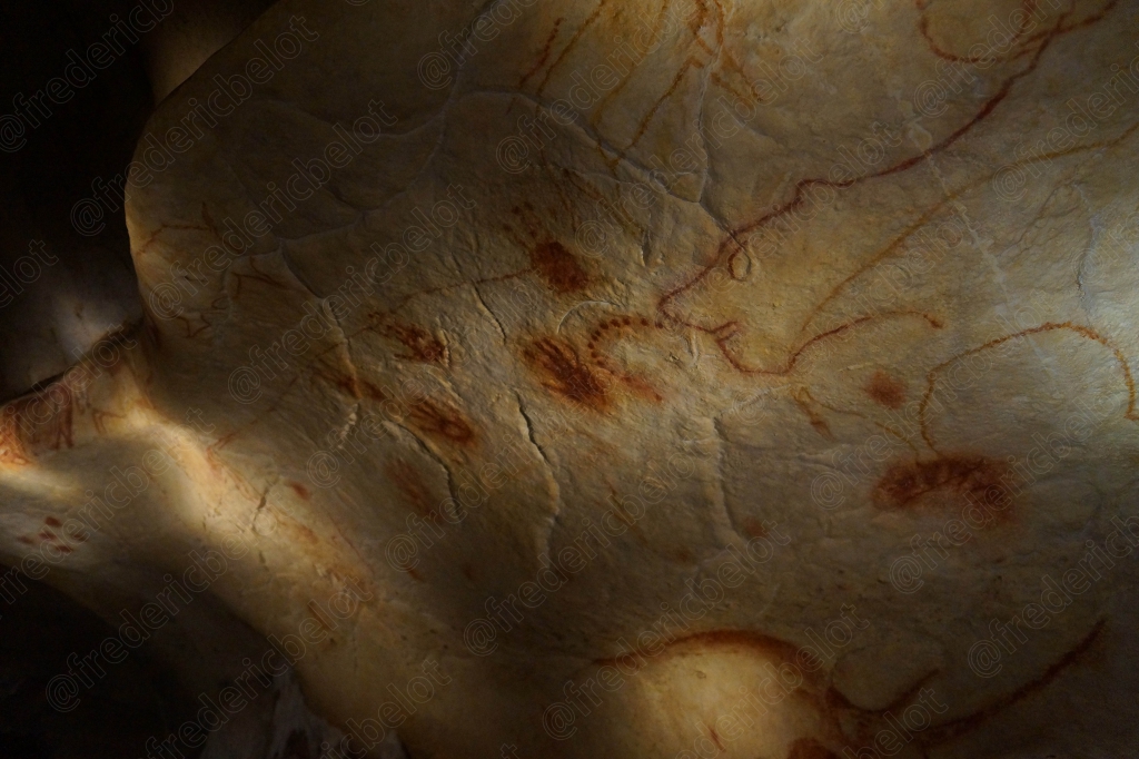 Traces ocre et rouges sur la roche, entre motifs abstraits et empreintes anciennes.