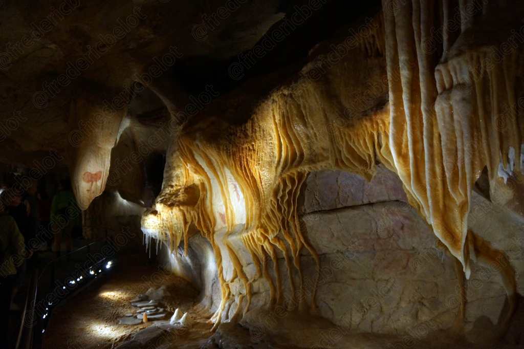 Stalactites et concrétions calcaires dorées scintillent sous l'éclairage de la grotte.