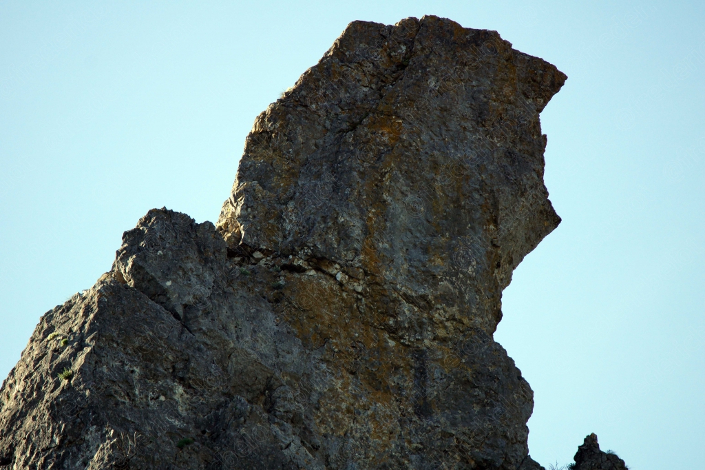 Un rocher sculpté par l'érosion se dresse en pointe contre un ciel clair.