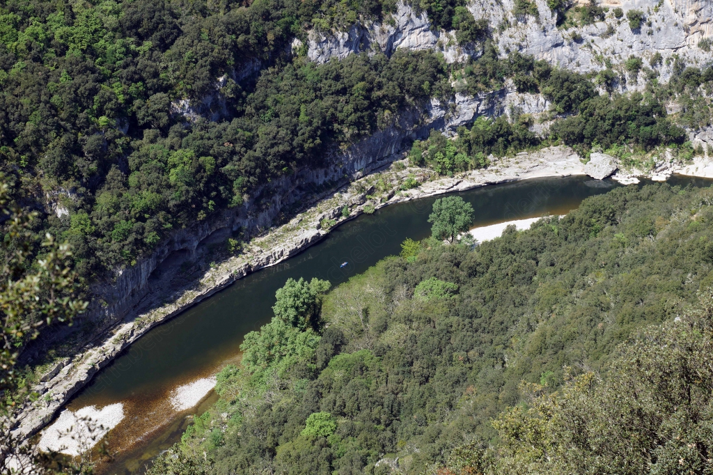 La rivière dessine une large boucle entre les falaises calcaires couvertes de forêt.