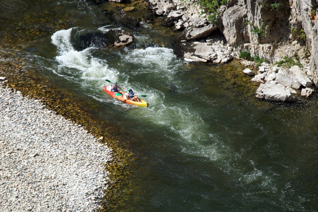 Un kayak jaune franchit un rapide écumant près d'un banc de galets.