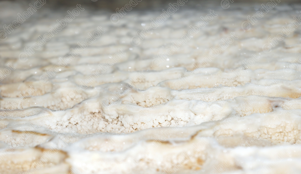Détail rapproché d'une surface rocheuse cristalline et humide, dans une grotte.