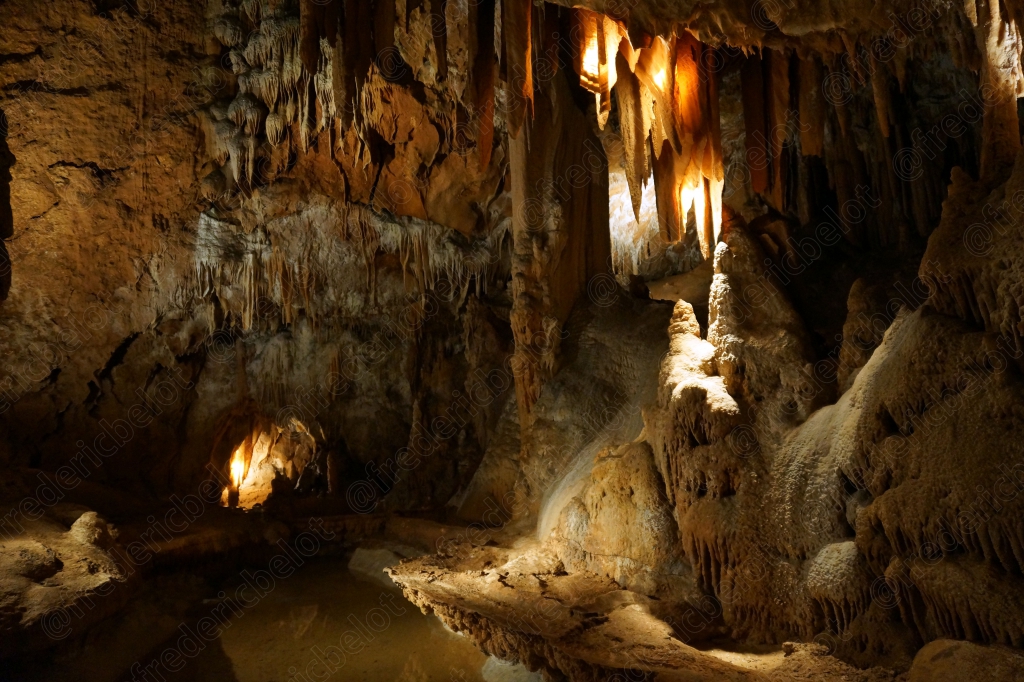Vue d'ensemble d'une galerie de grotte éclairée, stalactites et stalagmites se rejoignant par endroits.