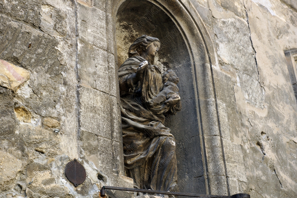 Une statue religieuse nichée dans une niche de pierre, à l'entrée d'un édifice ancien.