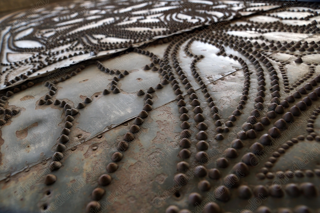 Détail ornemental en fer forgé aux motifs floraux sur une porte ancienne.