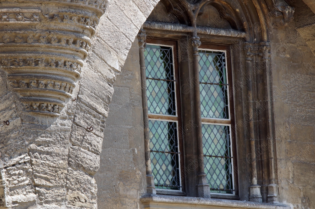 Détail architectural d'une fenêtre à meneaux sur une façade en pierre ancienne.