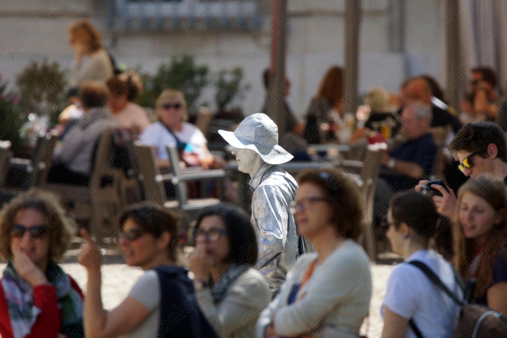 Un groupe de visiteurs discute sur une place, le Palais des Papes en arrière-plan.