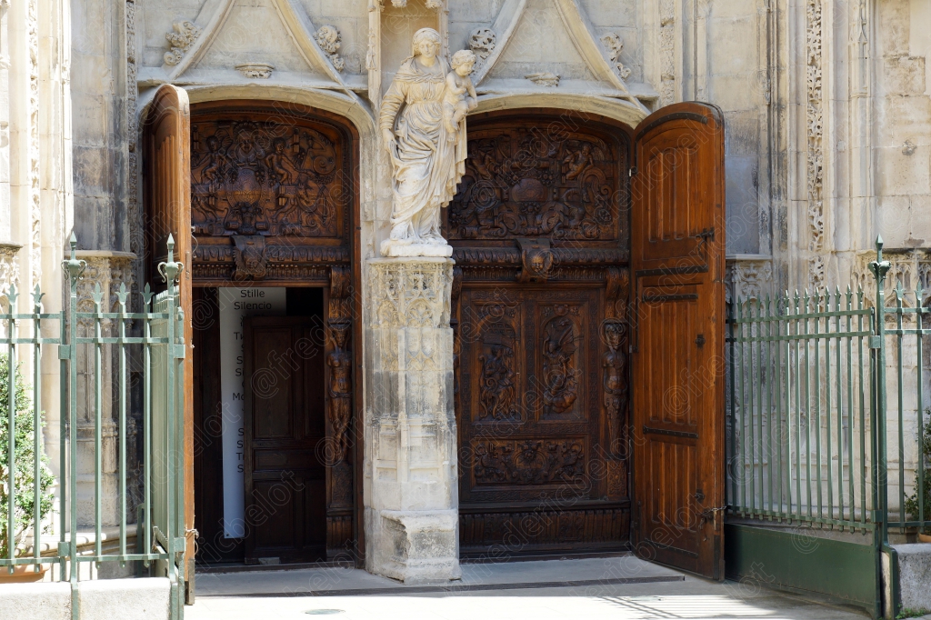 Un portail en bois sculpté, encadré de statues, à l'entrée d'un édifice religieux.