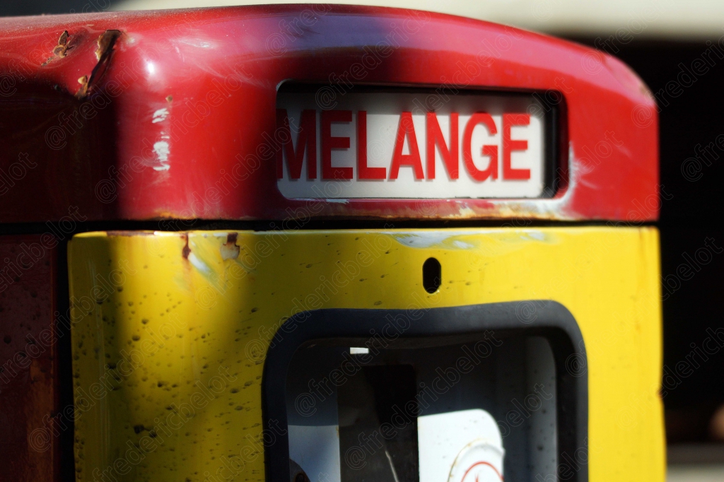 Une ancienne pompe à essence "Mélange" rouge et jaune, patinée par le temps.