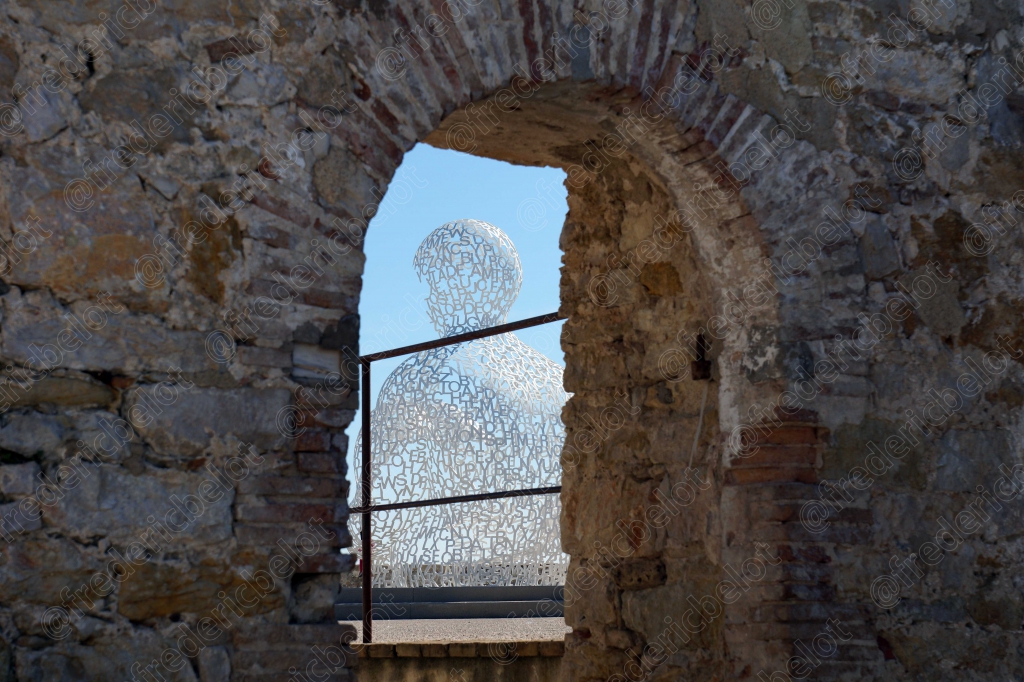 Une silhouette sculptée apparaît à travers l'arche en pierre d'un ancien édifice.