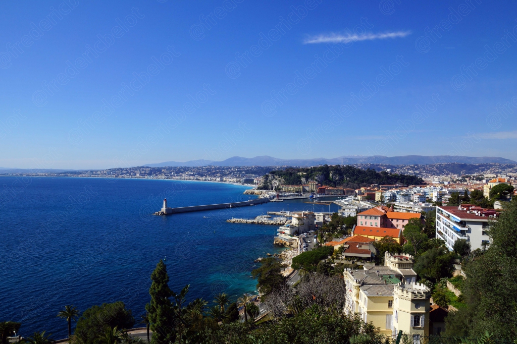 Vue en hauteur sur une ville côtière méditerranéenne, son phare et sa jetée.