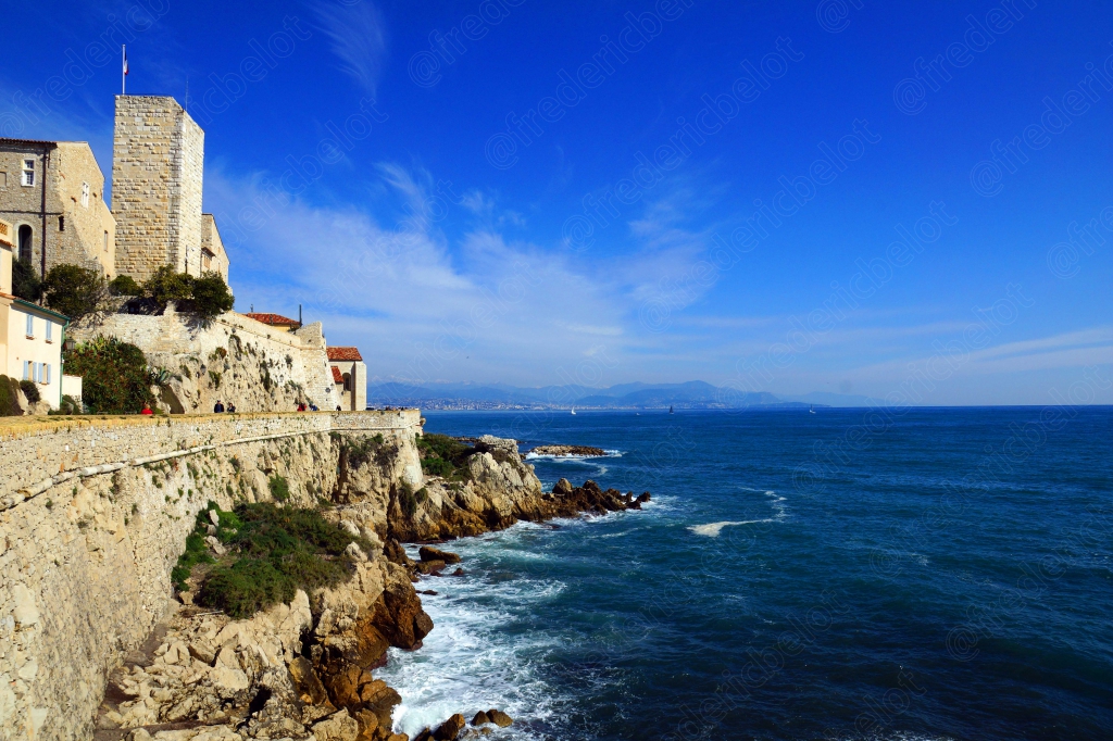 Les remparts d'une vieille ville fortifiée dominent la Méditerranée depuis un promontoire rocheux.