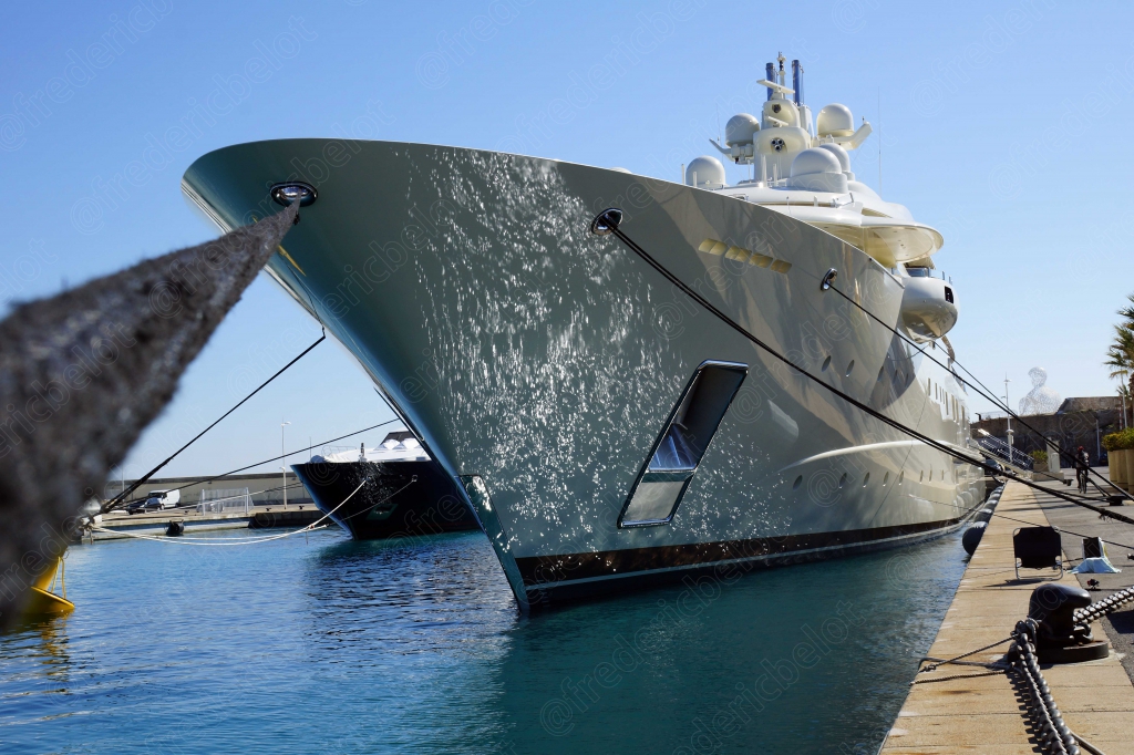 La proue argentée d'un grand yacht amarré dans un port.