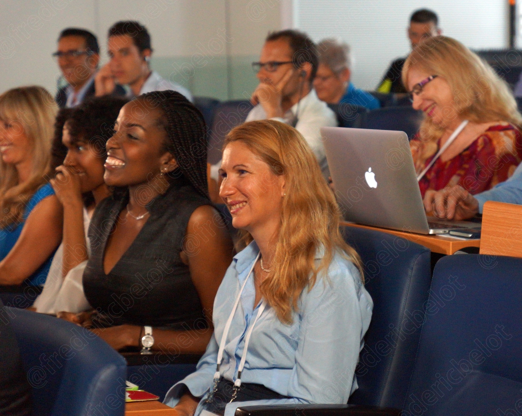 Des participants assis suivent une présentation, ordinateur portable ouvert au premier plan.