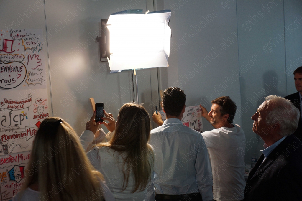 Des participants prennent des photos d'une fresque murale, éclairage de studio en place.
