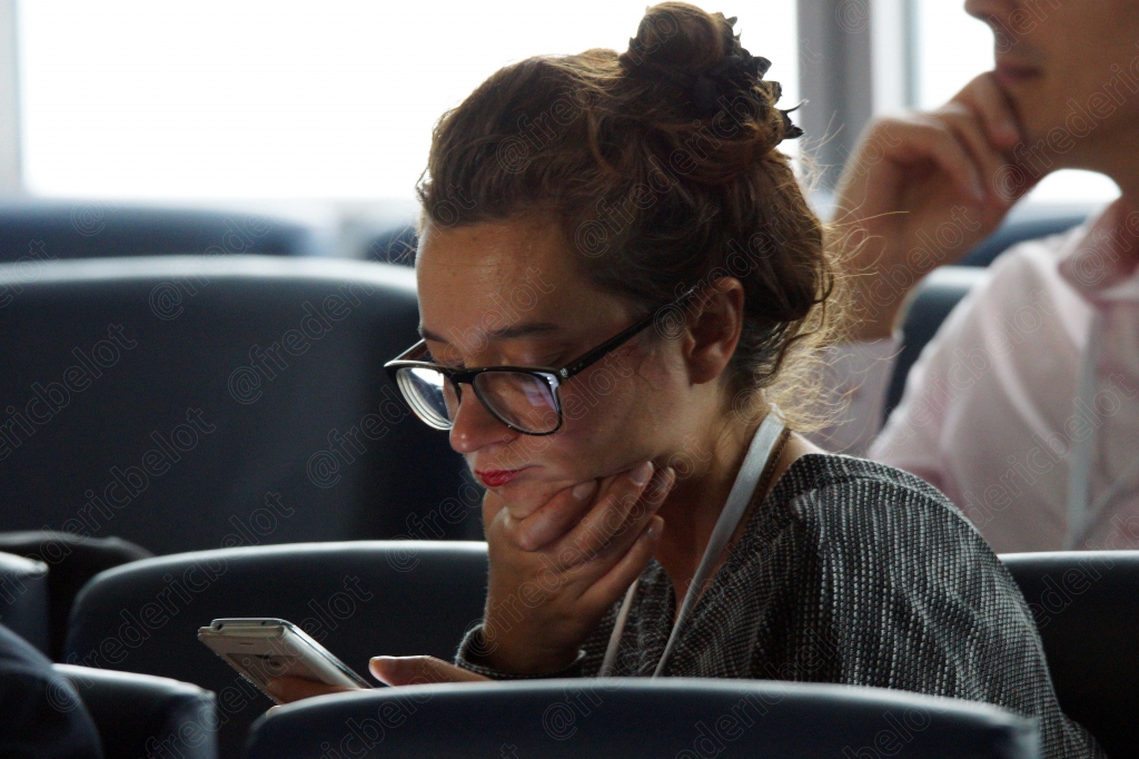 Portrait d'une femme à lunettes, pensive, dans la salle de conférence.