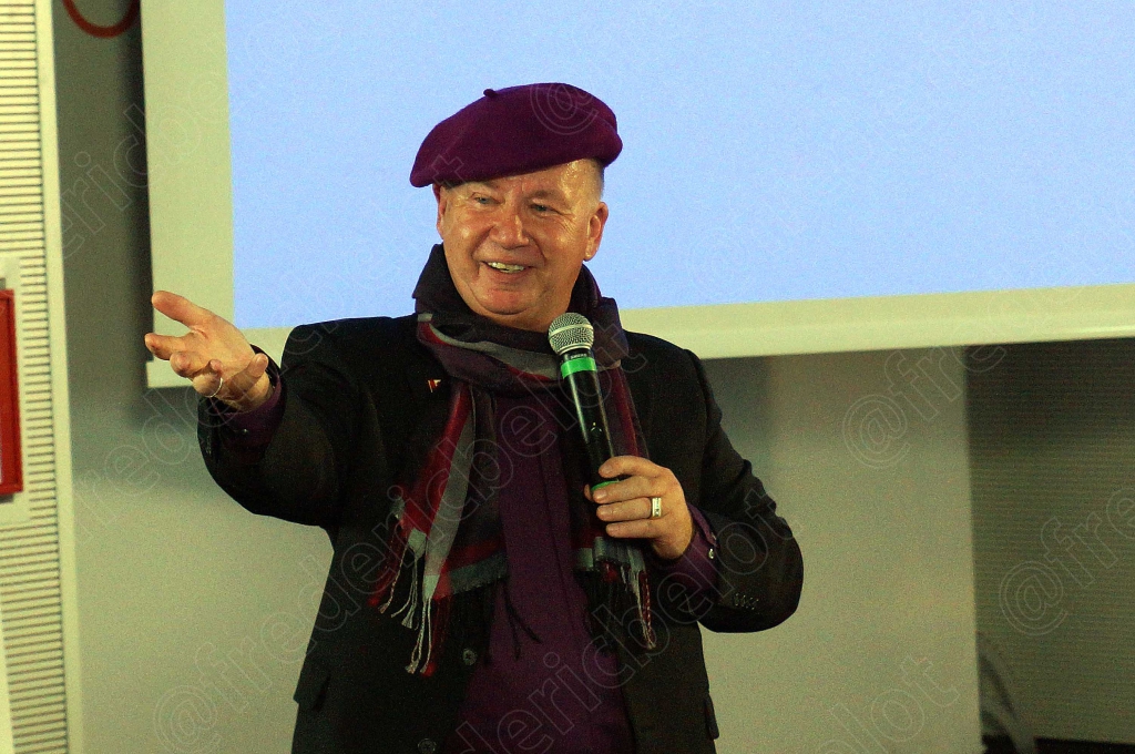 Le même homme au béret violet poursuit sa présentation avec entrain.