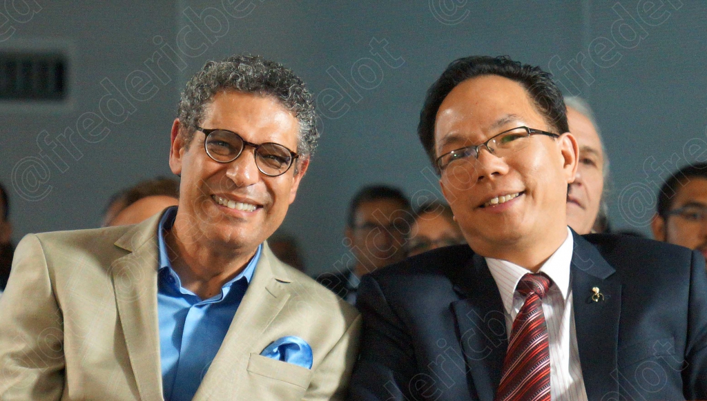 Deux hommes en costume se donnent une accolade amicale, souriants.