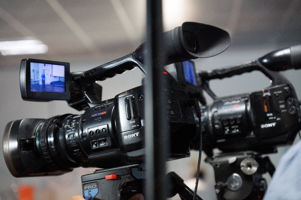 Un cadreur filme la scène avec une caméra Sony sur trépied.