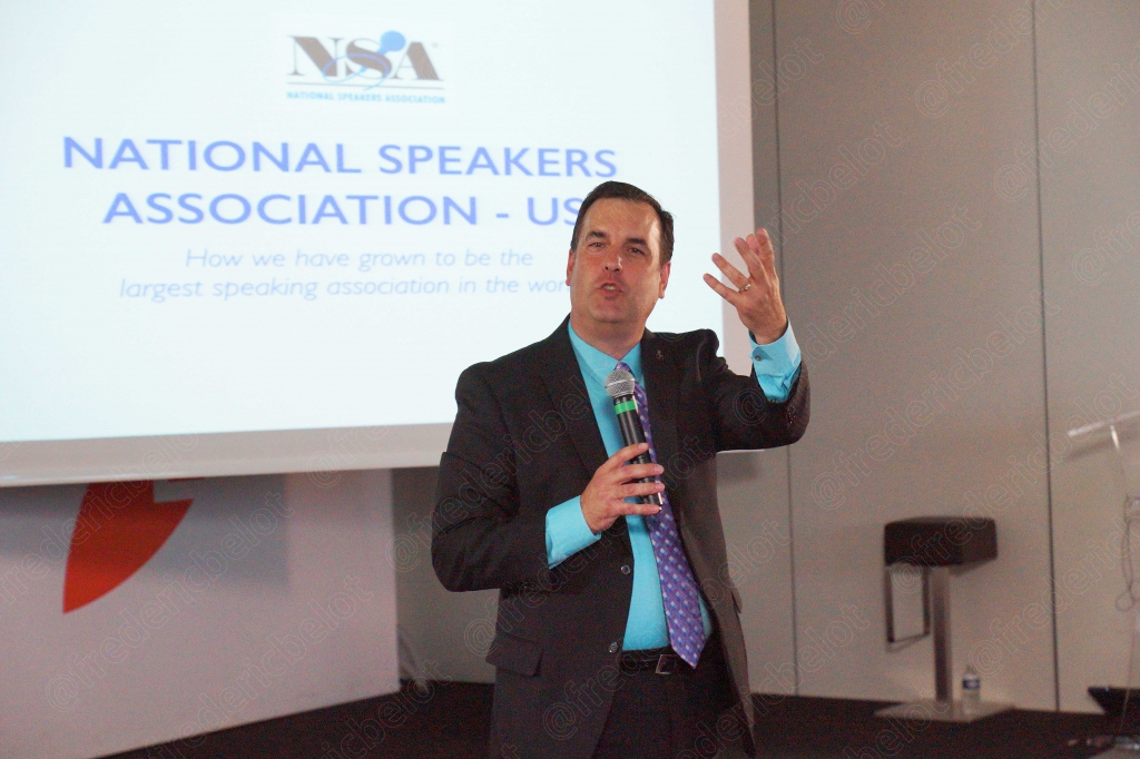 Un écran affiche le logo de la National Speakers Association (USA) pendant une intervention.
