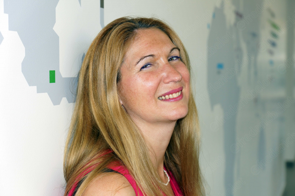 Portrait d'une femme blonde souriante, regard tourné vers le haut, dans une lumière douce.