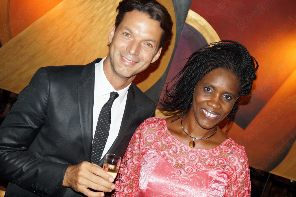 Un homme en cuir noir et une femme en robe rose posent ensemble devant le photo call.