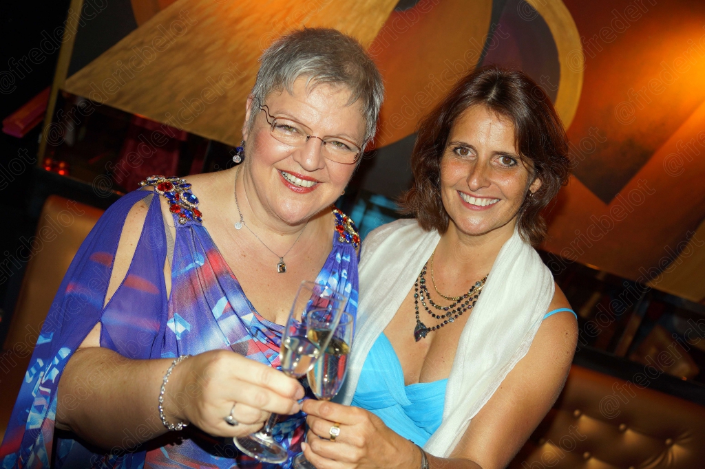 Deux femmes en robe posent ensemble, l'une en bleu, l'autre en étole blanche.