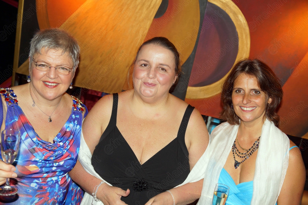 Trois femmes en robe de soirée posent ensemble devant le photo call.