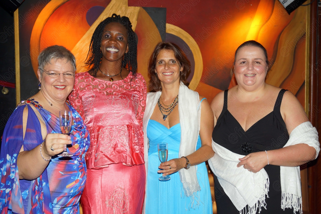 Quatre personnes en tenue de soirée posent ensemble, coupes de champagne en main.