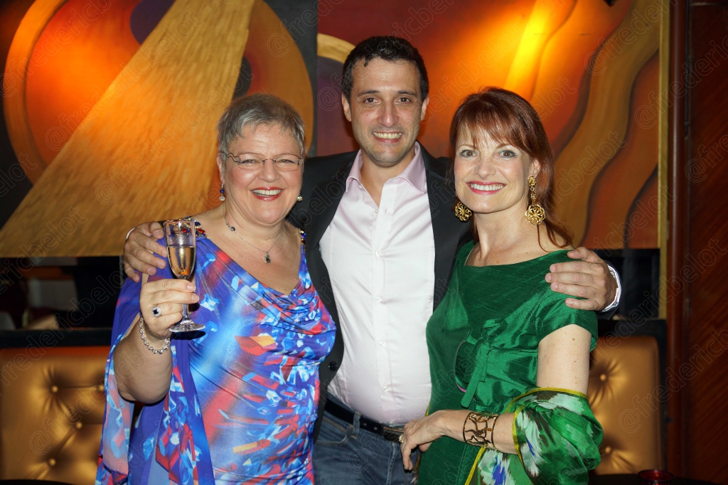 Trois convives se serrent l'un contre l'autre, coupe de champagne à la main, dans une ambiance de soirée chaleureuse.