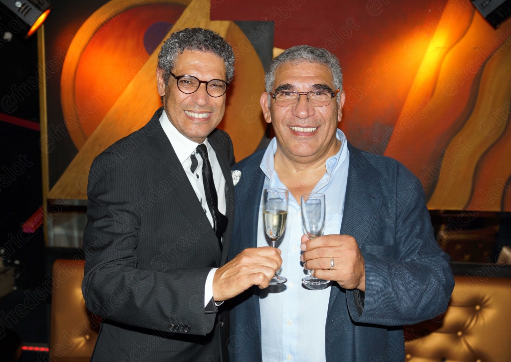 Deux hommes en costume trinquent ensemble devant le photo call.
