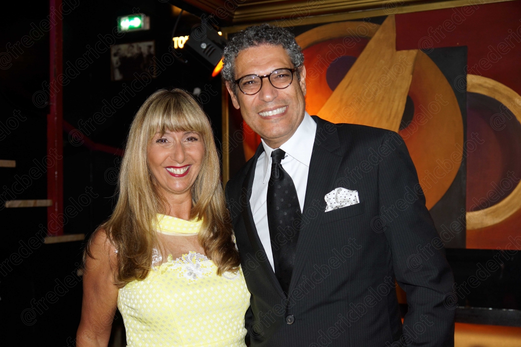 Une femme en robe jaune pose avec un homme en smoking, souriants.