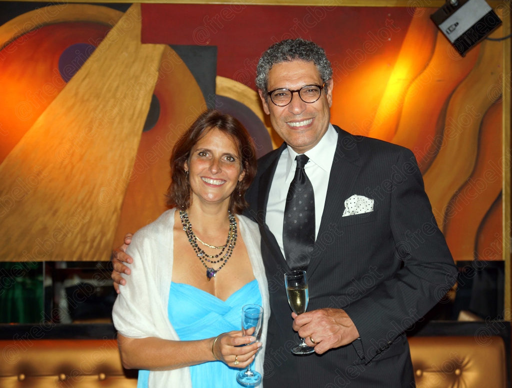 Une femme en étole bleue et un homme en costume posent ensemble, souriants.