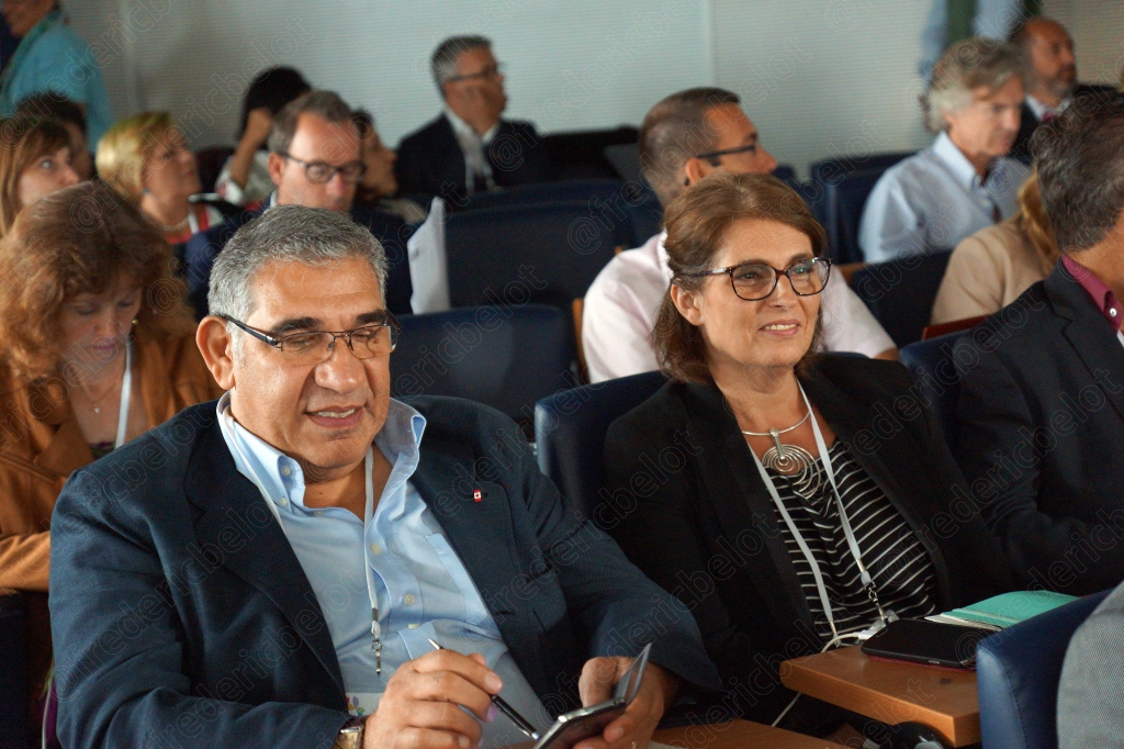 Deux hommes assis dans le public écoutent attentivement la conférence.