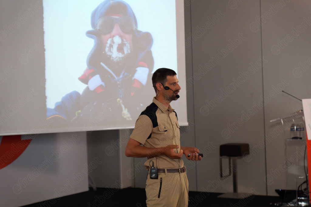 Une projection montre un homme en tenue d'exploration polaire, un intervenant commente devant l'écran.