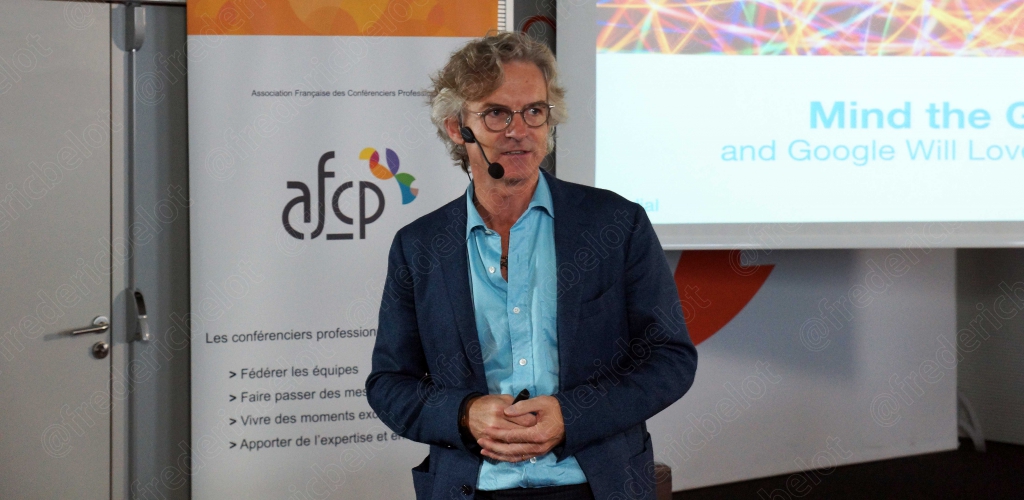 Homme en chemise bleu clair devant un écran de projection