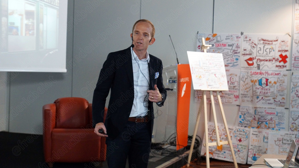 Homme debout près d'un chevalet couvert de post-it colorés, écran de mind-mapping