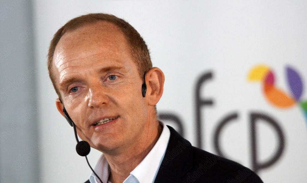 Homme portant un micro-casque, devant le logo afcp