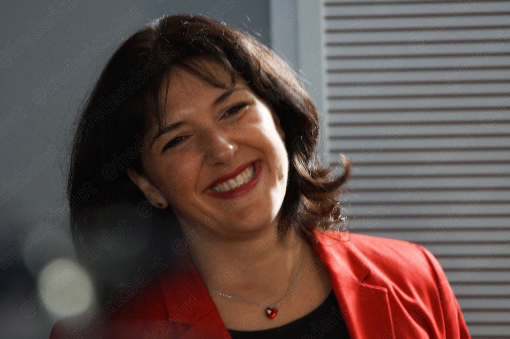 Femme aux cheveux bruns souriante, en veste rouge, gros plan