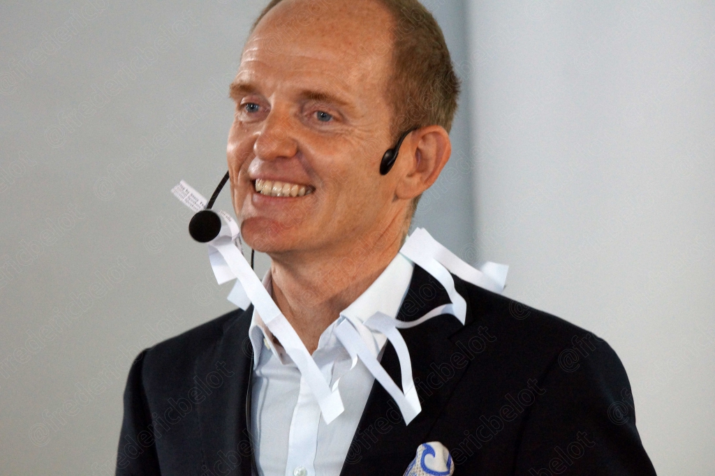 Homme au micro-casque souriant, morceaux de papier collés sur sa veste