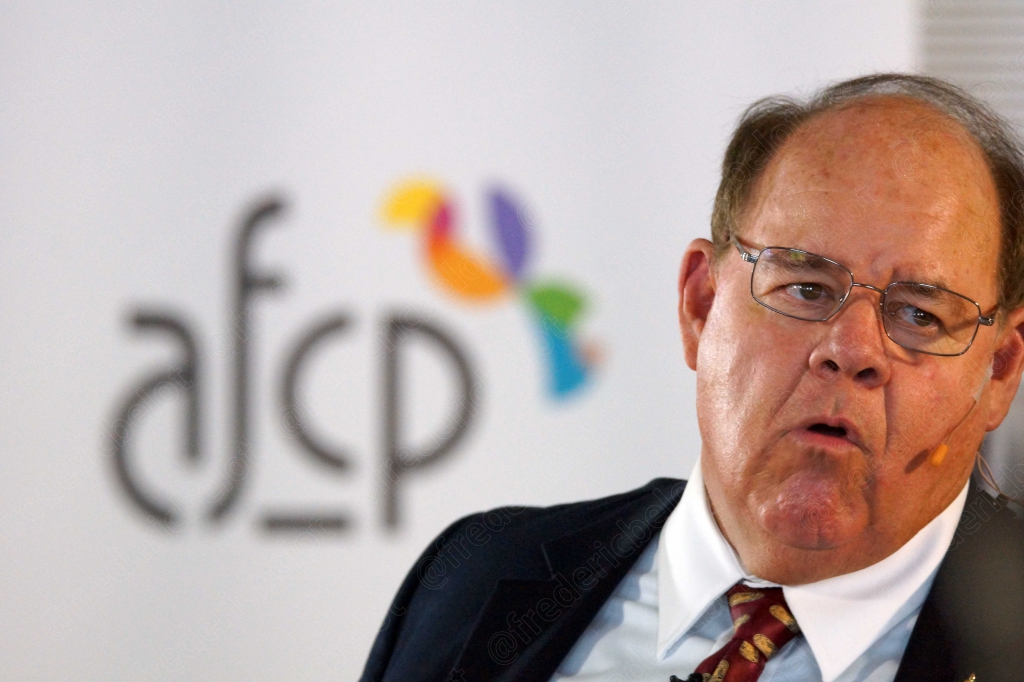Homme en costume à lunettes, expression pensive, devant le logo afcp