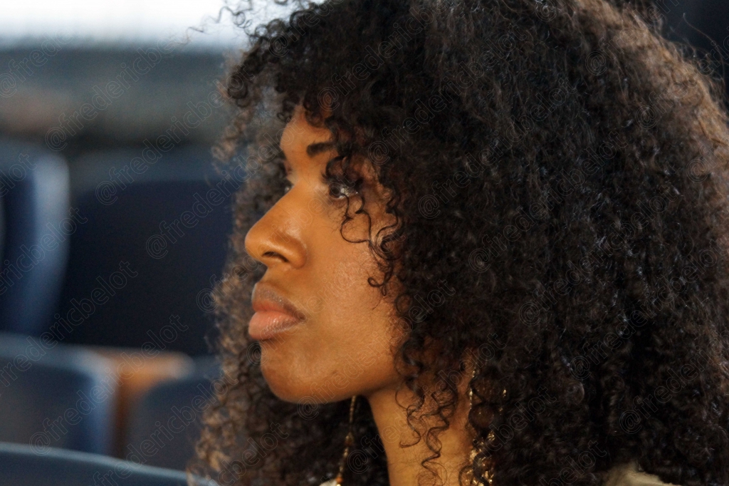 Femme aux cheveux bouclés, de profil, attentive dans le public