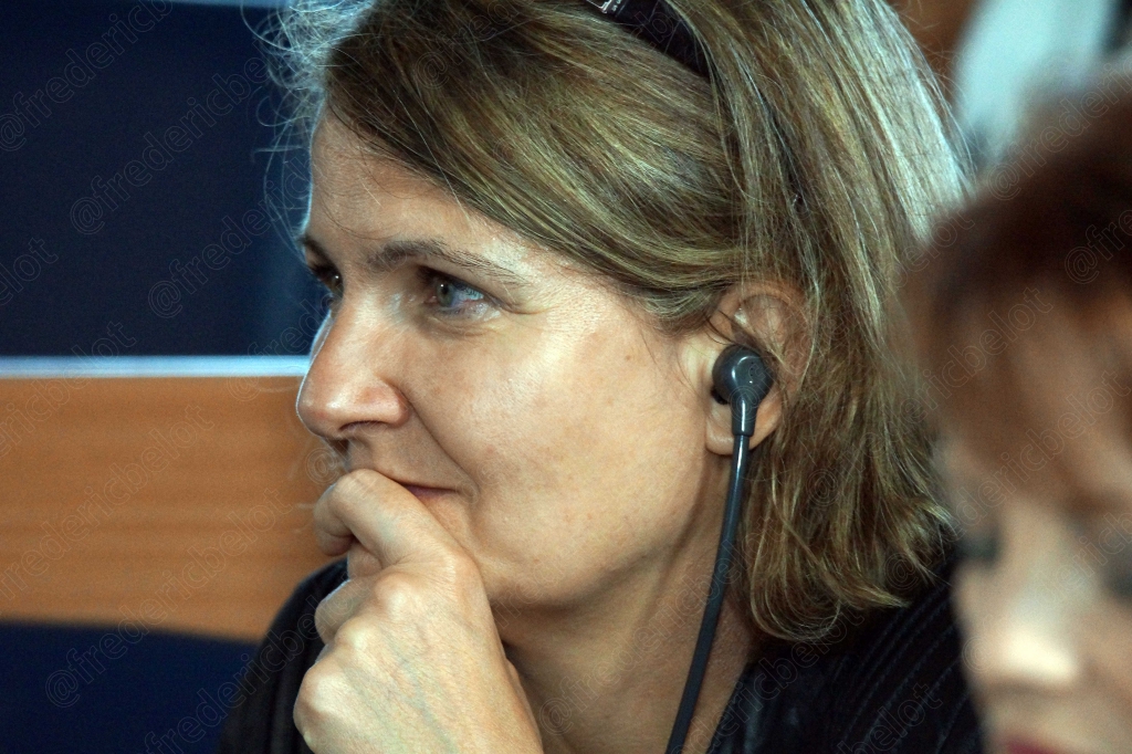 Femme aux cheveux blonds avec micro-casque, menton sur la main, attentive