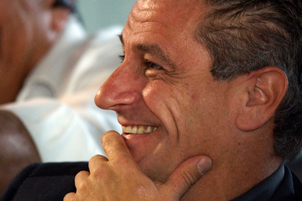 Homme souriant de profil, main sur le menton, dans le public